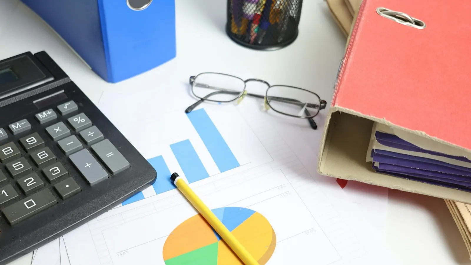 Desk with a calculator, printed charts and ring binders, representing preparing a UAE company for its annual audit
