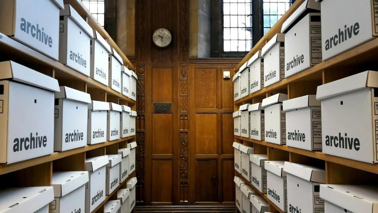 Rows of white archive boxes on wooden shelves, where records are kept after a company closes