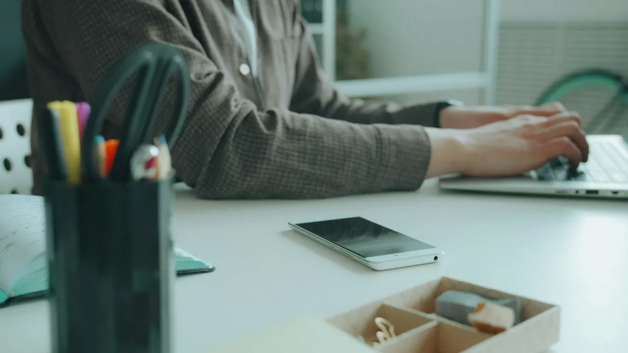 A person typing on a laptop at a desk, filling in an online application