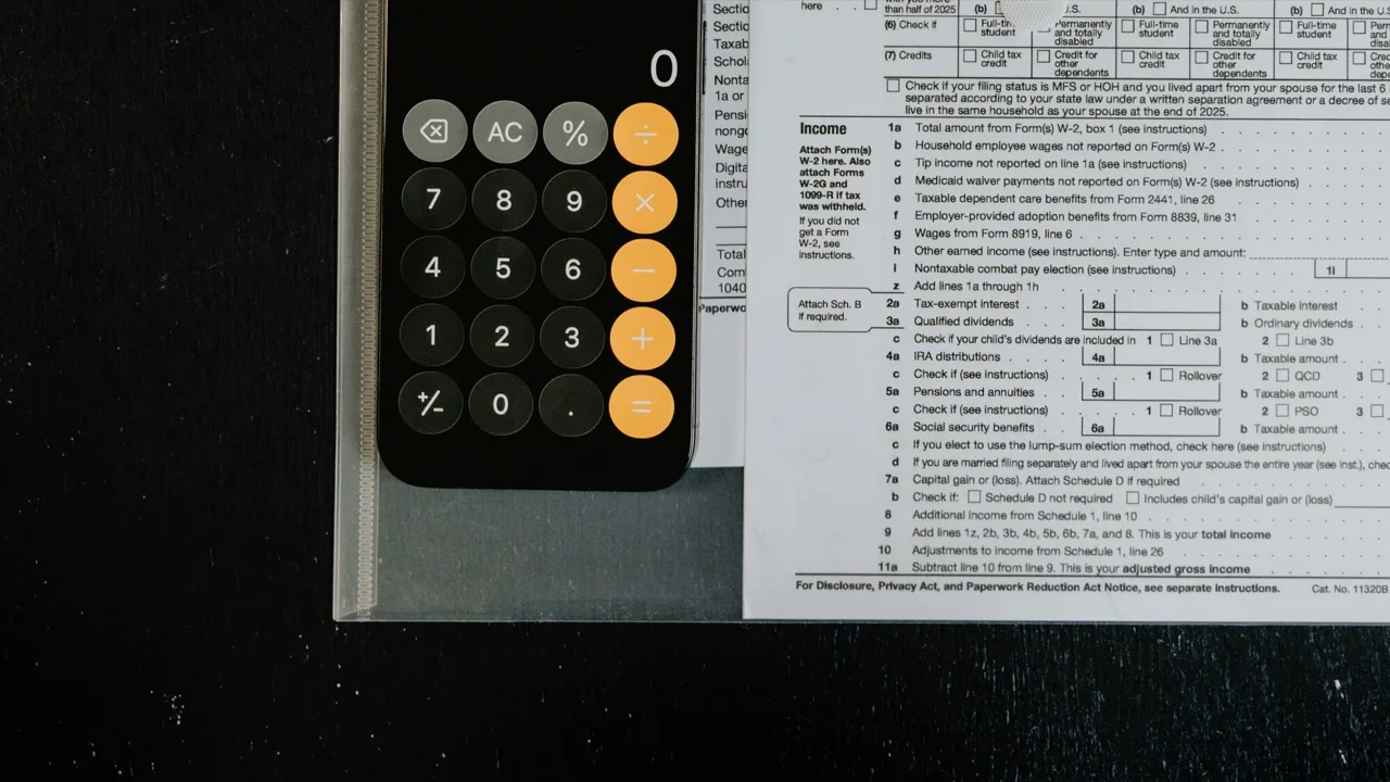 Une calculatrice à côté d'un formulaire de déclaration fiscale sur un bureau sombre