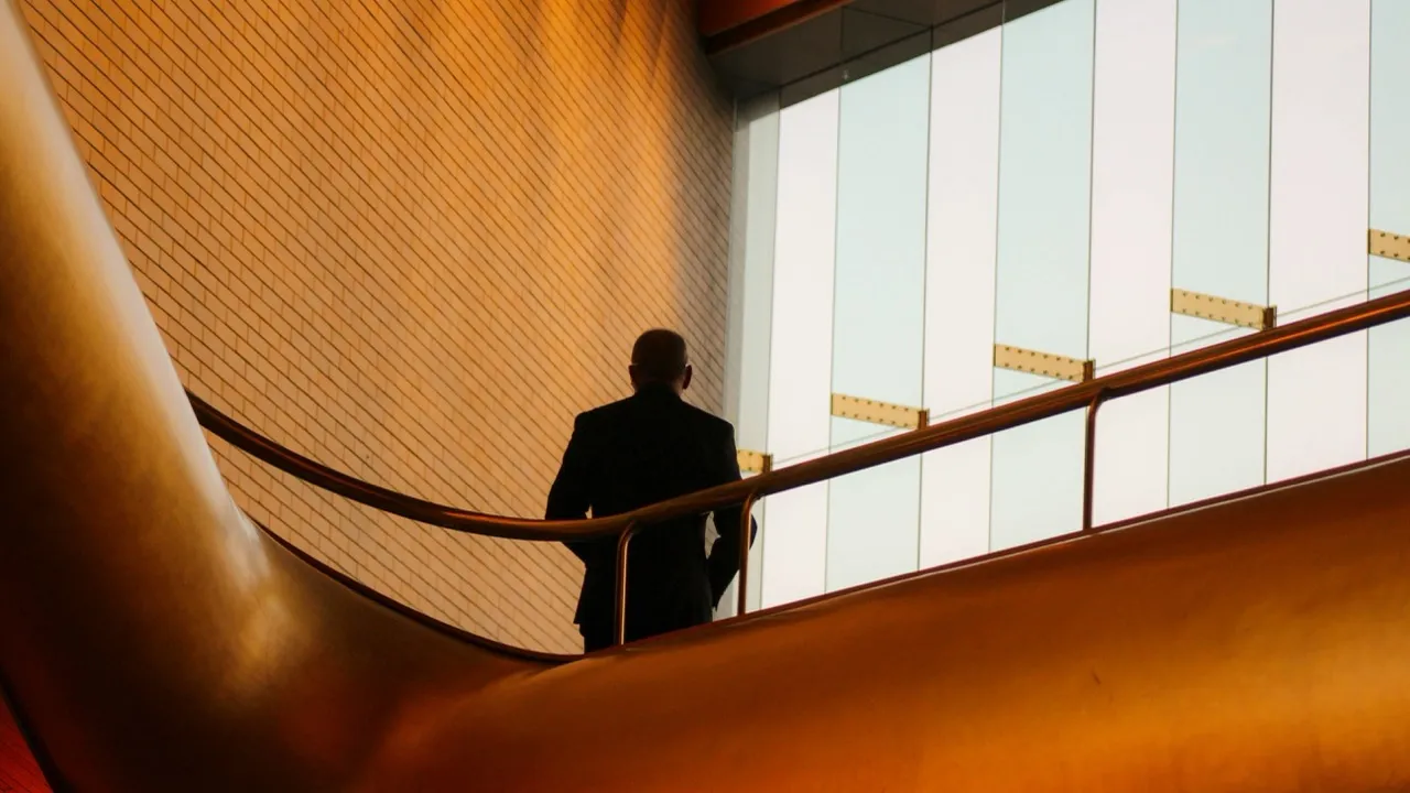 A businessperson descending a modern curved staircase in an office building